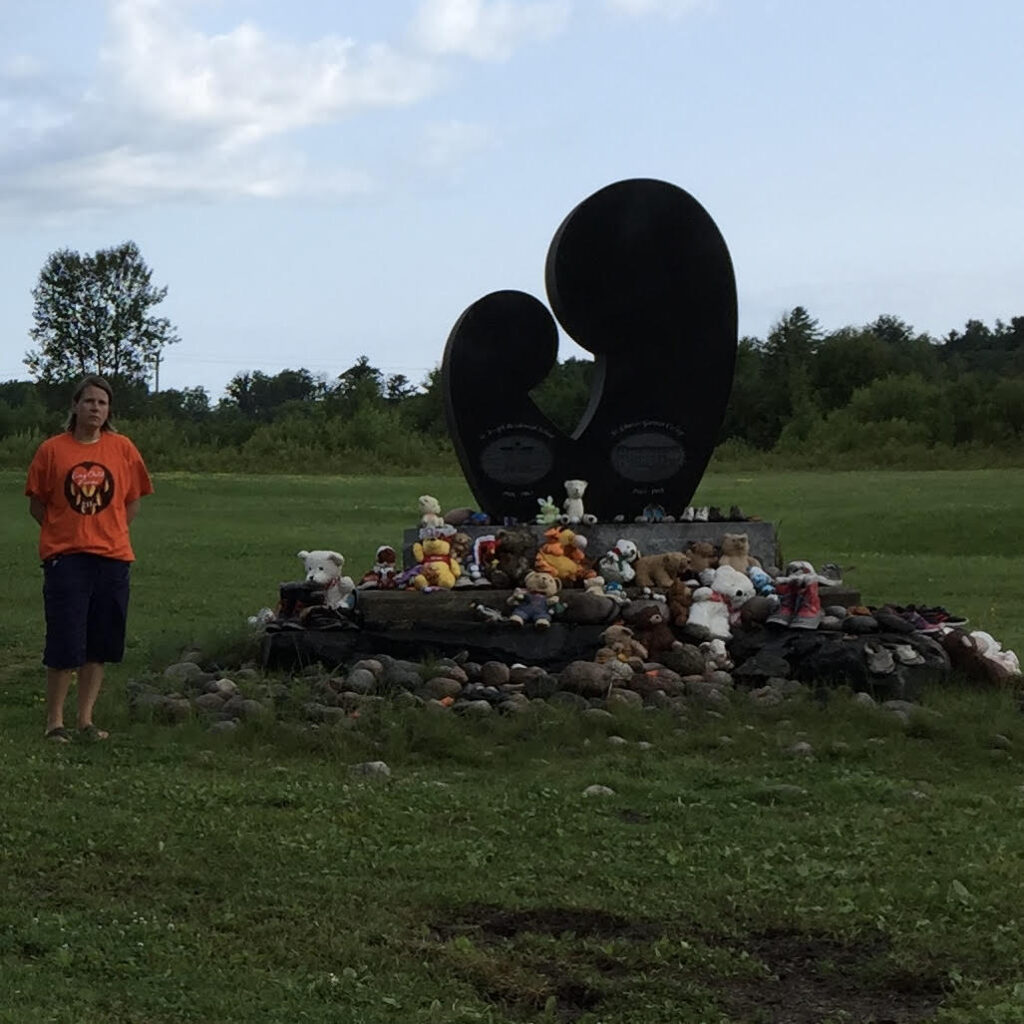 Laura Chesnick standing at a monument to the survivors of St Joseph's Residential school in Spanish Ontario, 2022